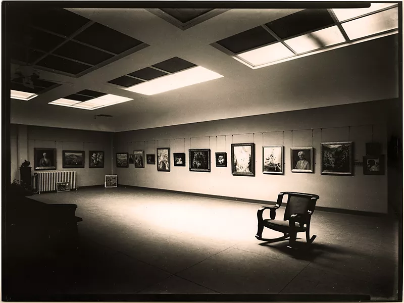 An art exhibition, with framed paintings lining the wall.
