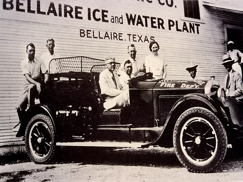 Men sitting in a car in front of the Bellaire Ice and Water Plant